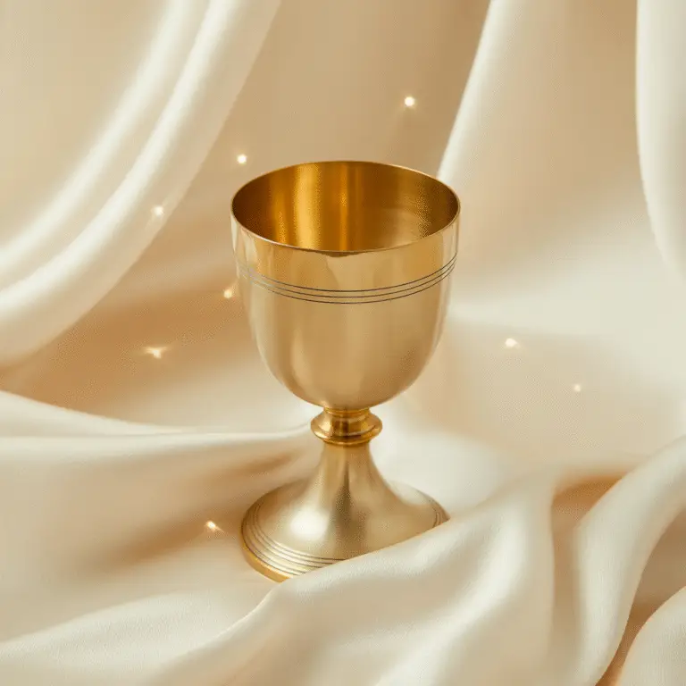 A golden chalice resting on soft ivory fabric with gentle light reflections, symbolizing the Vessel of Wound — the sacred container of pain, compassion, and transformation.